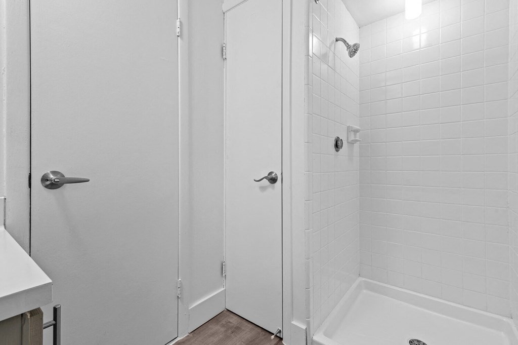 a white bathroom with a shower and a sink