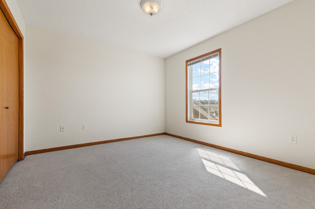 an empty living room with a window and carpet
