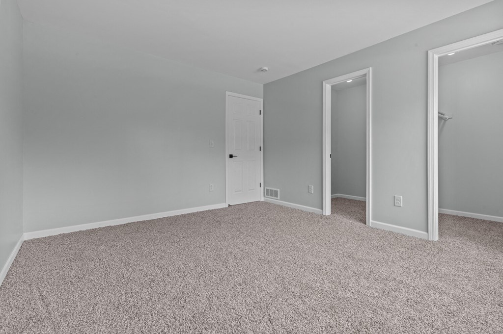 a bedroom with a carpeted floor and two closet doors