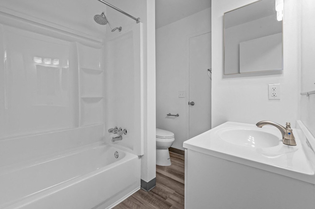 a white bathroom with a tub and a sink and a toilet