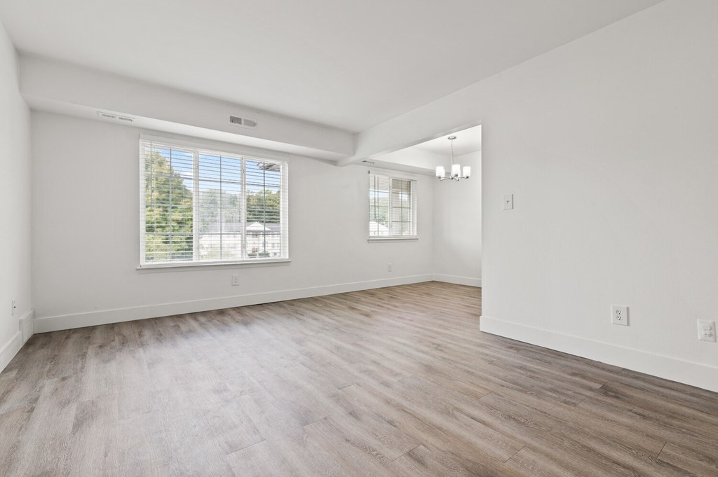 the living room and dining room in a new home with white walls and wood floors