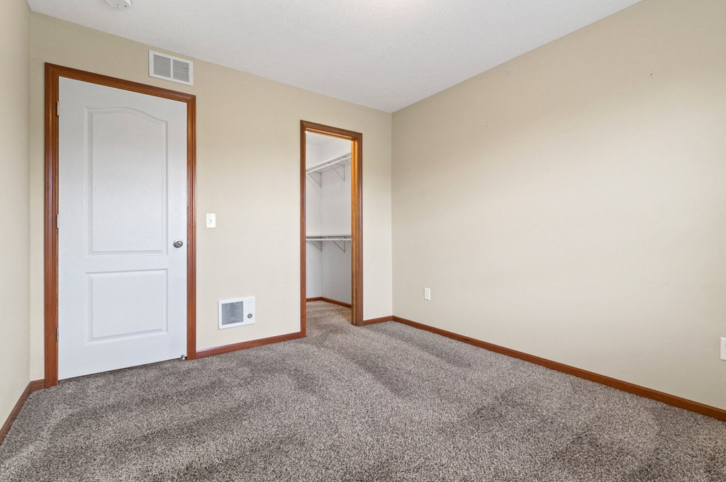a bedroom with carpet and a door to a closet