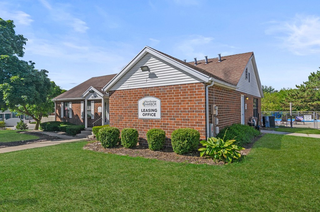 a small brick house with a lawn and a sidewalk in front of it