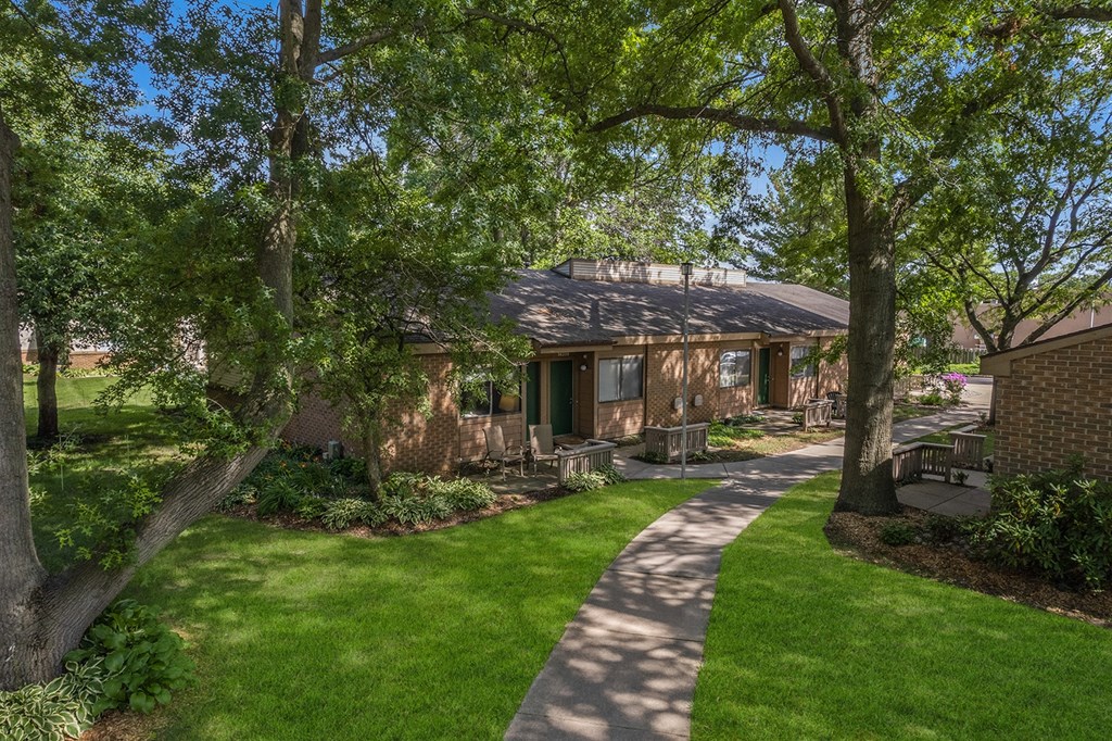 a pathway leading to a brown house with trees