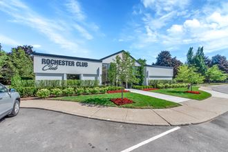 the front of rochester club club building with a sidewalk and landscaping with trees
