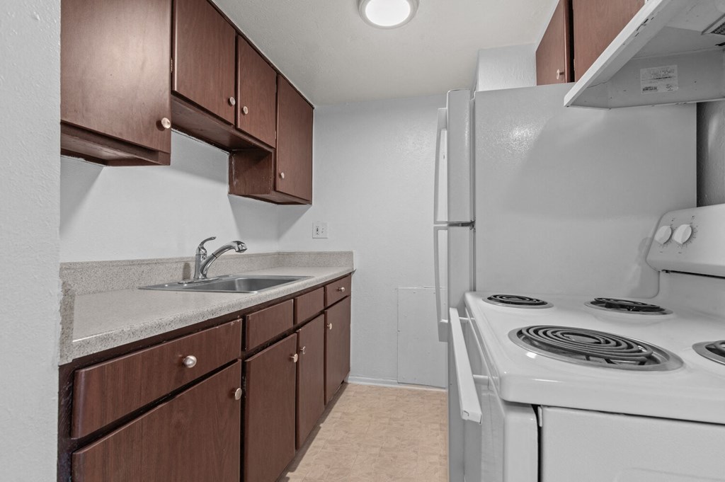 an empty kitchen with a stove refrigerator and sink