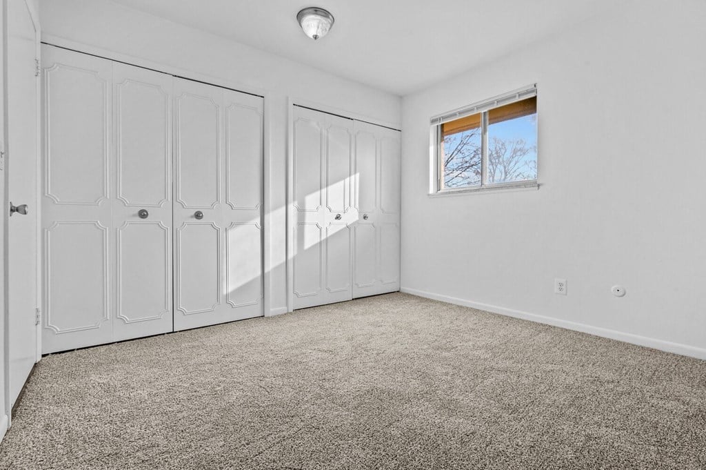 an empty room with white walls and white closets and a window