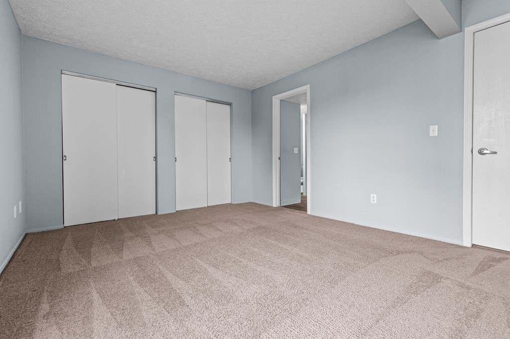 the living room of an apartment with carpet and blue walls  at Fairfax Apartments - Lansing, MI, Lansing, 48917