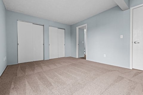 the living room of an apartment with carpet and blue walls