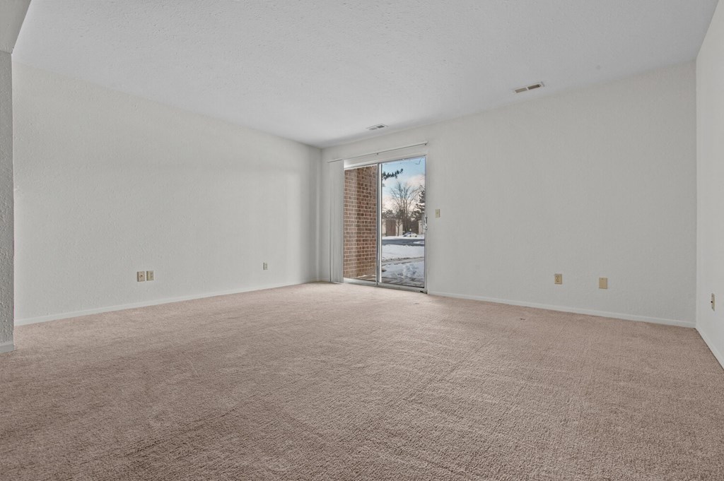 an empty living room with a door to a balcony