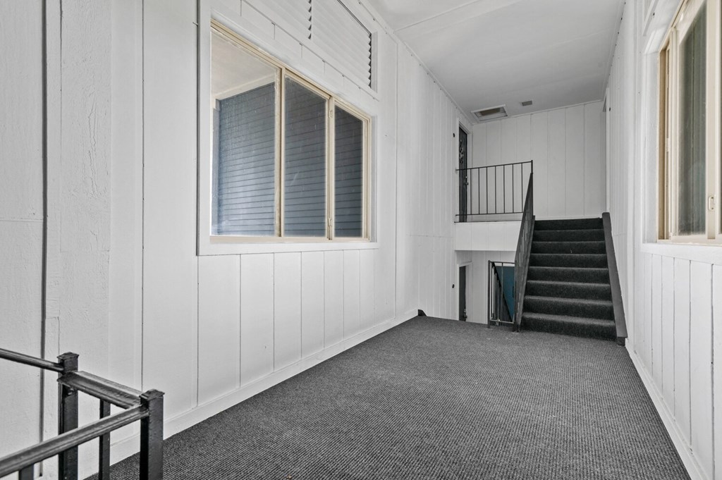 a large white room with a staircase and a window