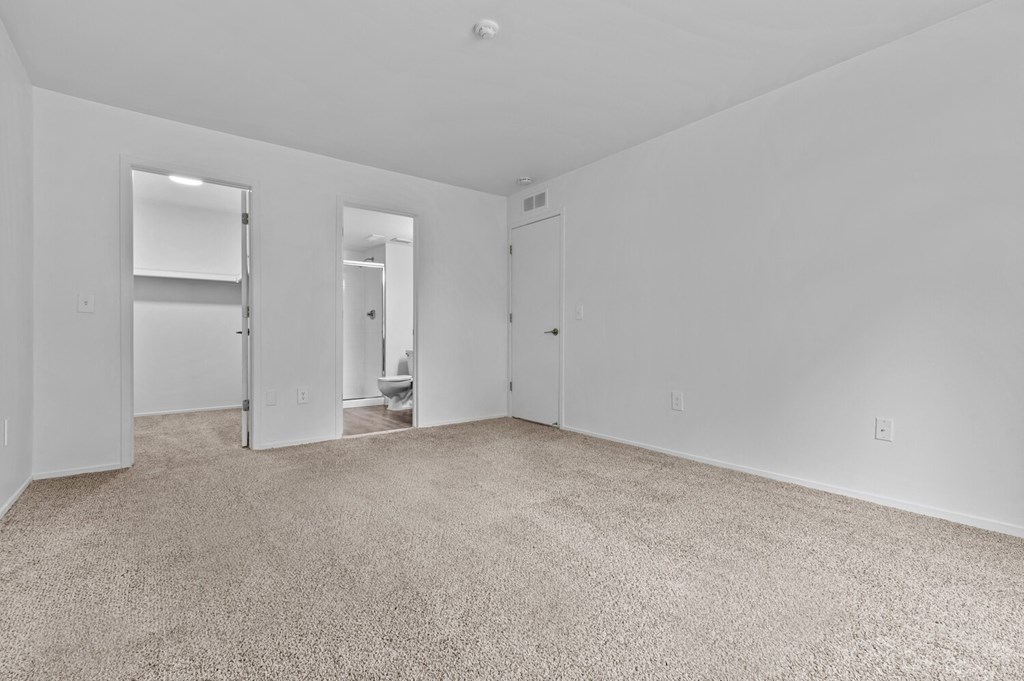 a bedroom with white walls and carpet