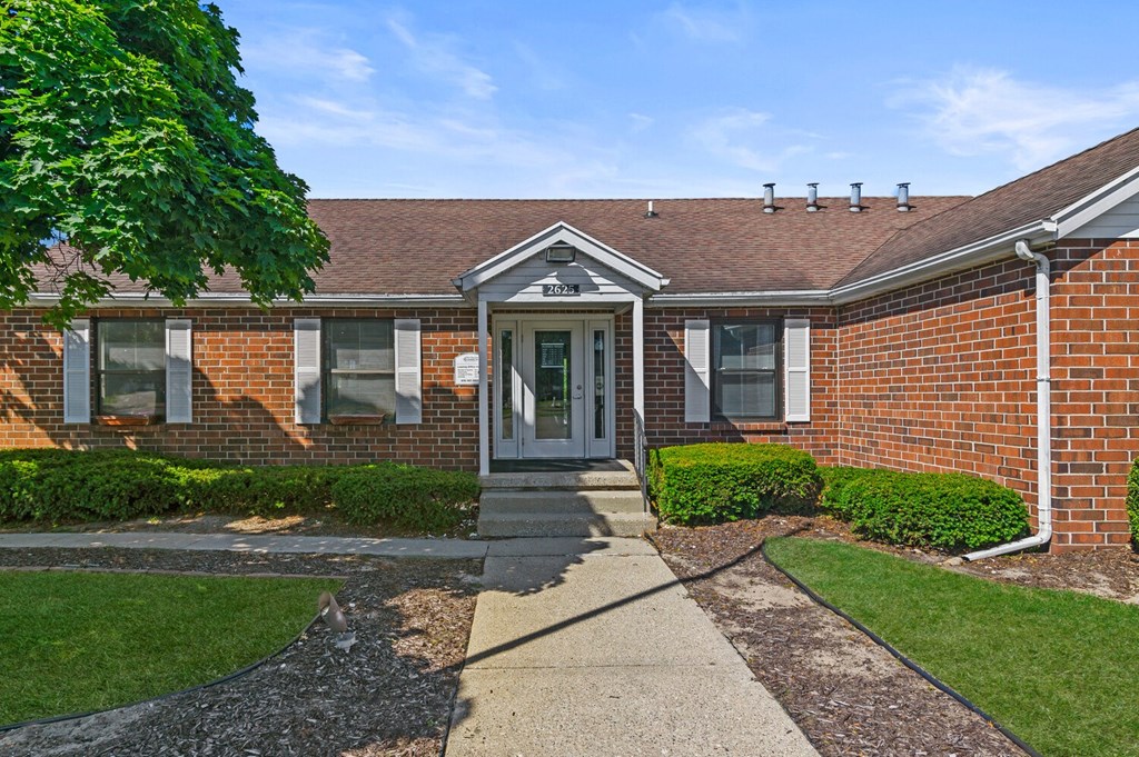 an exterior view of a brick building with a sidewalk and grass