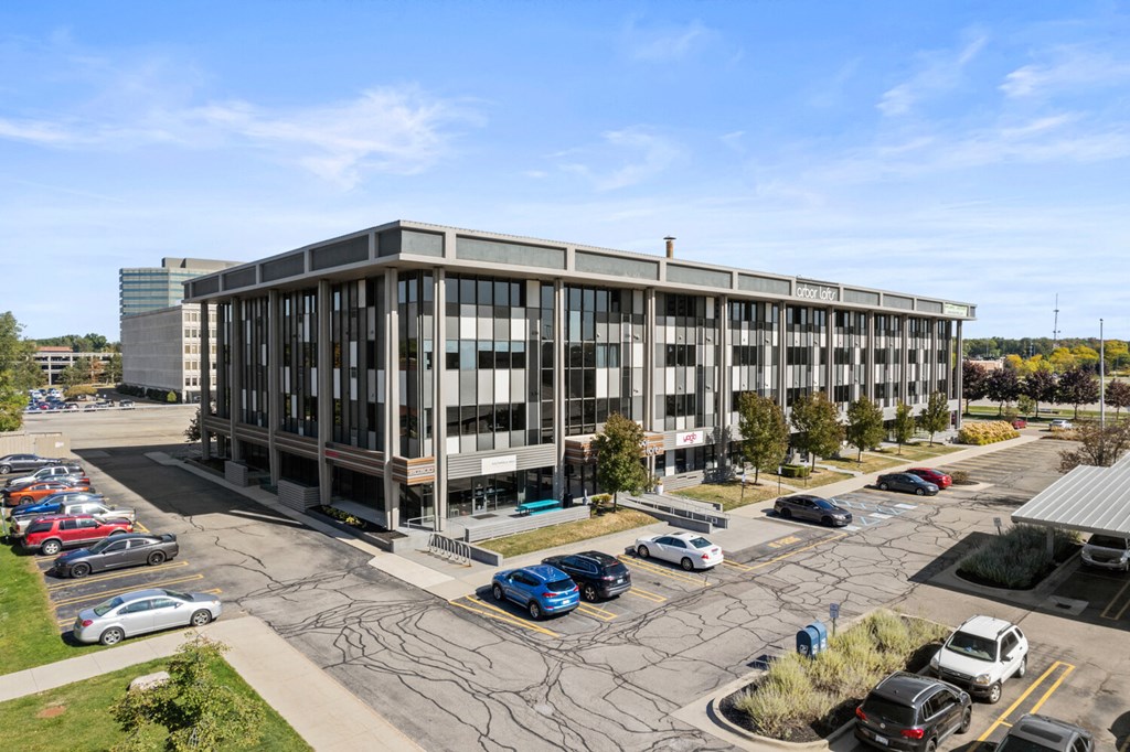 an office building with a parking lot with cars