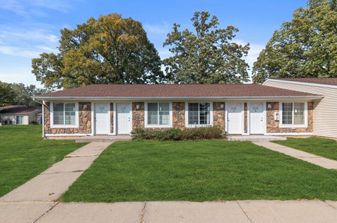 the front of a brick house with white doors and a lawn