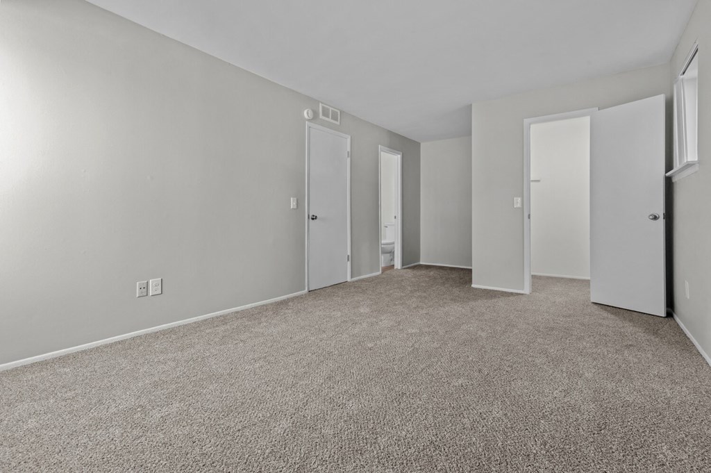 the living room of an apartment with carpeting and white doors