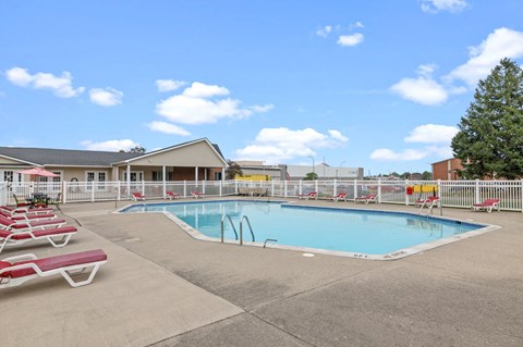 a swimming pool with chaise lounge chairs and a building in the background