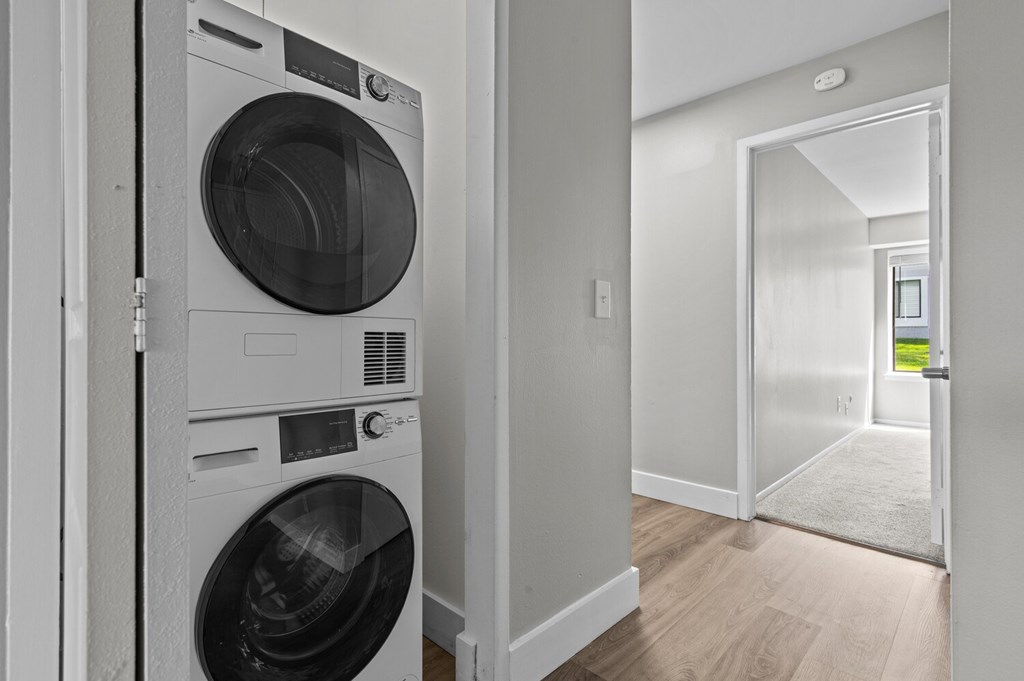 A white washing machine is in a narrow hallway.