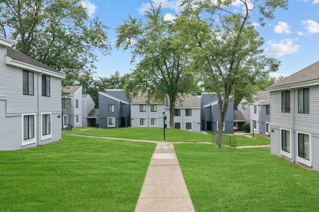a grassy area with trees and houses in the background