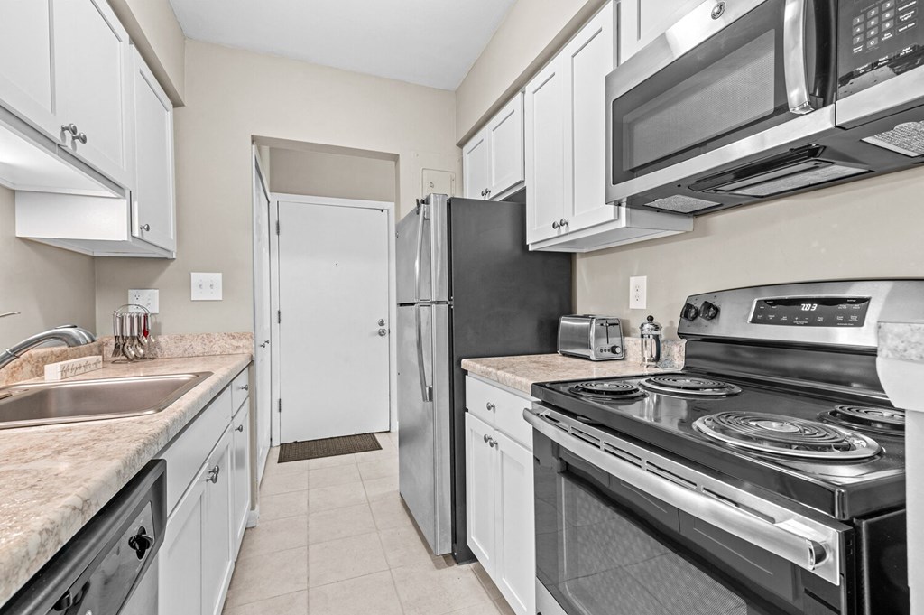 a kitchen with white cabinets and stainless steel appliances at Apple Ridge Apartments - Livonia, MI, Livonia, MI