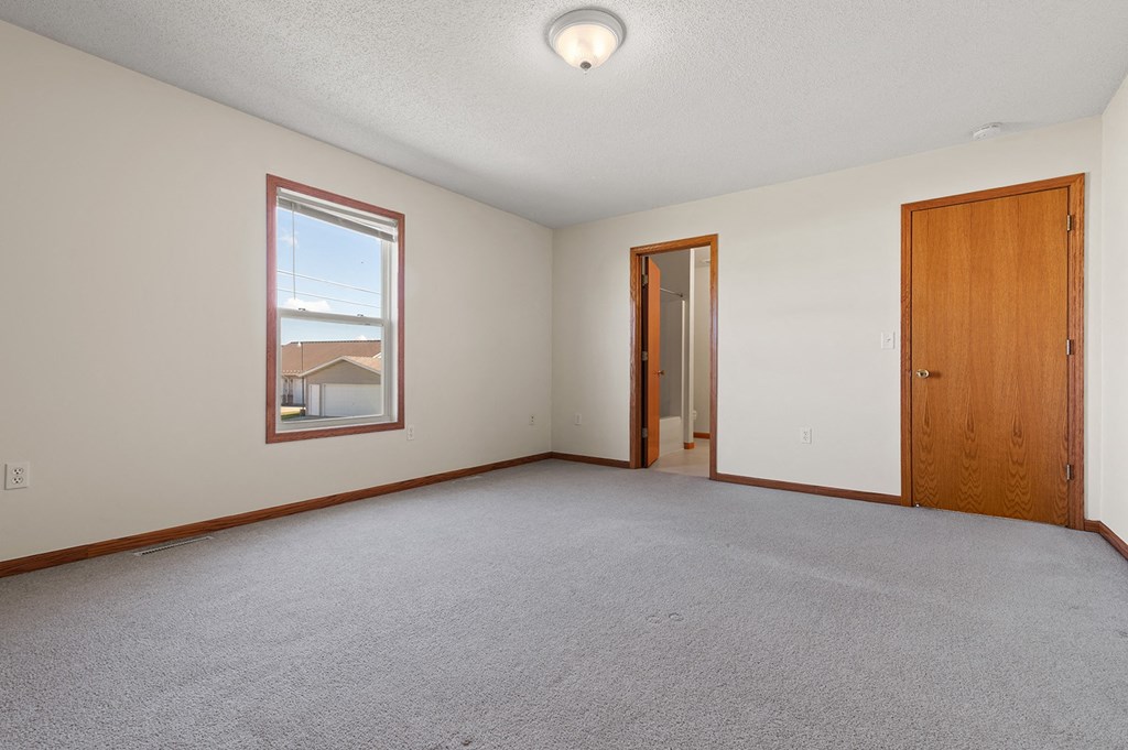 an empty living room with a door to a hallway and a window