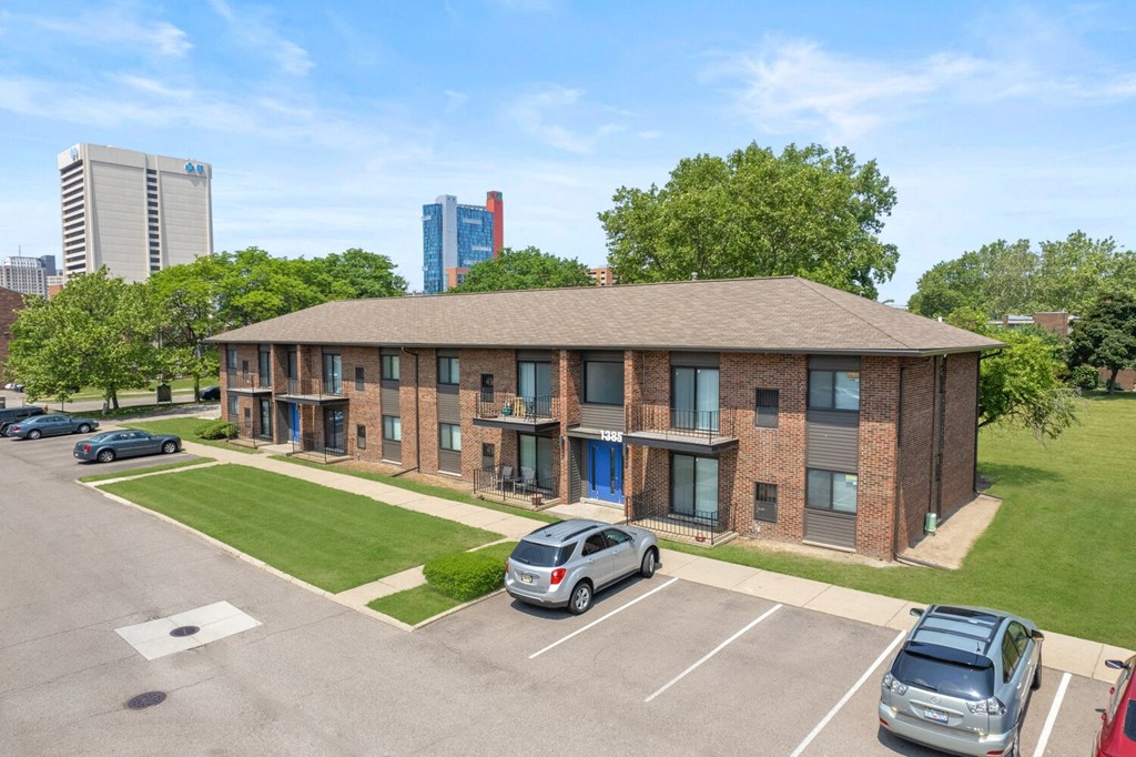 a brick apartment building with a lawn and cars parked in front of it at Lafayette Park Place, Detroit, MI