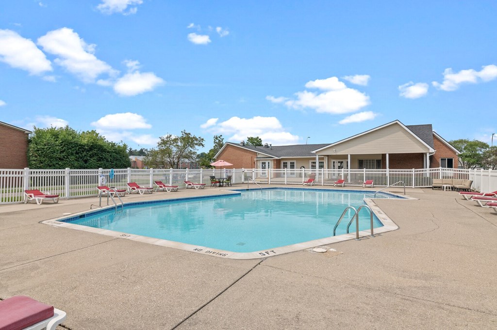 a swimming pool with chaise lounge chairs and a house in the background