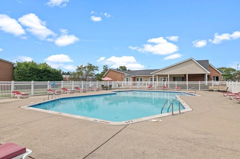 a swimming pool with chaise lounge chairs and a house in the background