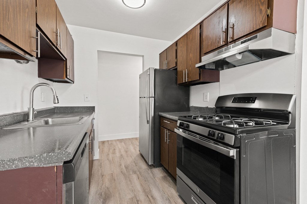 an empty kitchen with stainless steel appliances and wooden cabinets