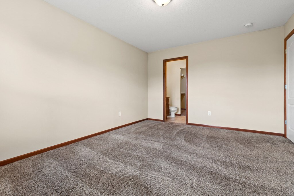 an empty living room with carpet and a door to a bathroom