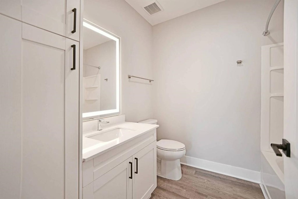 A white bathroom with a toilet, sink, and mirror.