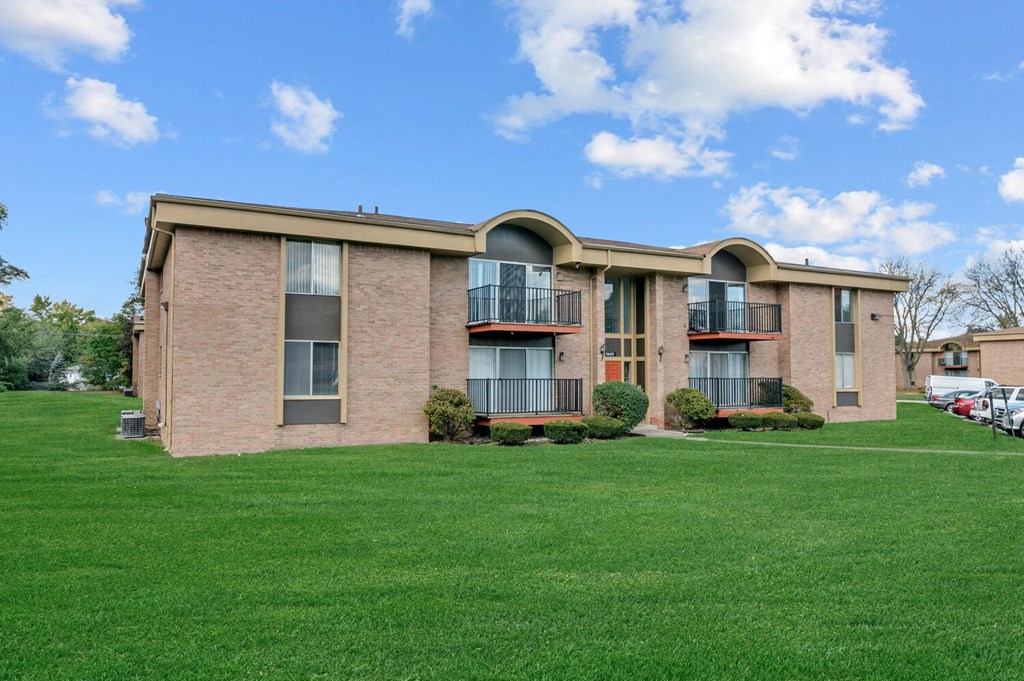 a brick apartment building with green grass in front of it