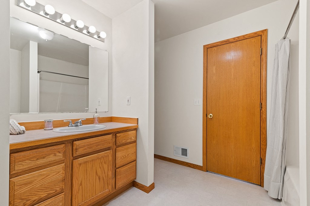 a bathroom with a sink and a mirror and a door