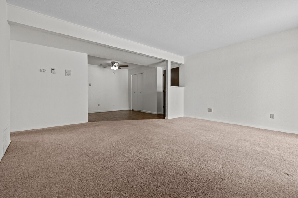 an empty living room with white walls and a beige carpet