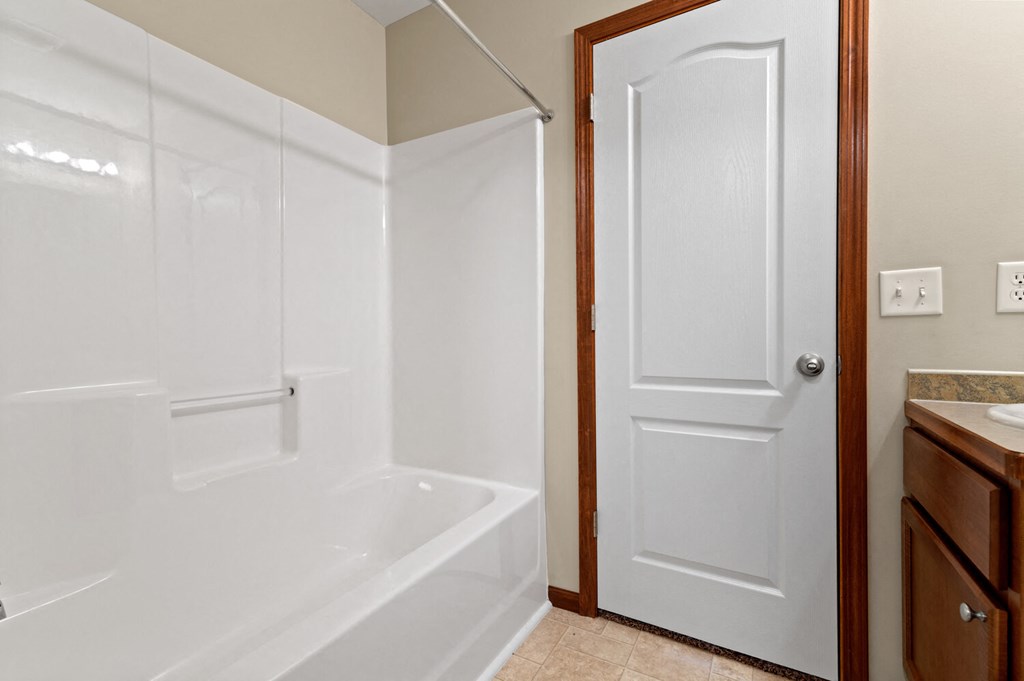 a bathroom with a white tub and shower and a sink