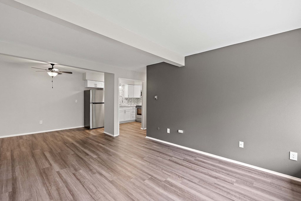 the living room and kitchen of a new home with wood floors and a ceiling fan