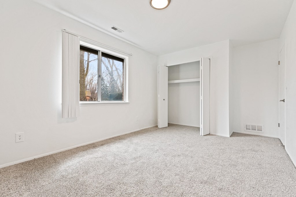 an empty living room with a window and a closet