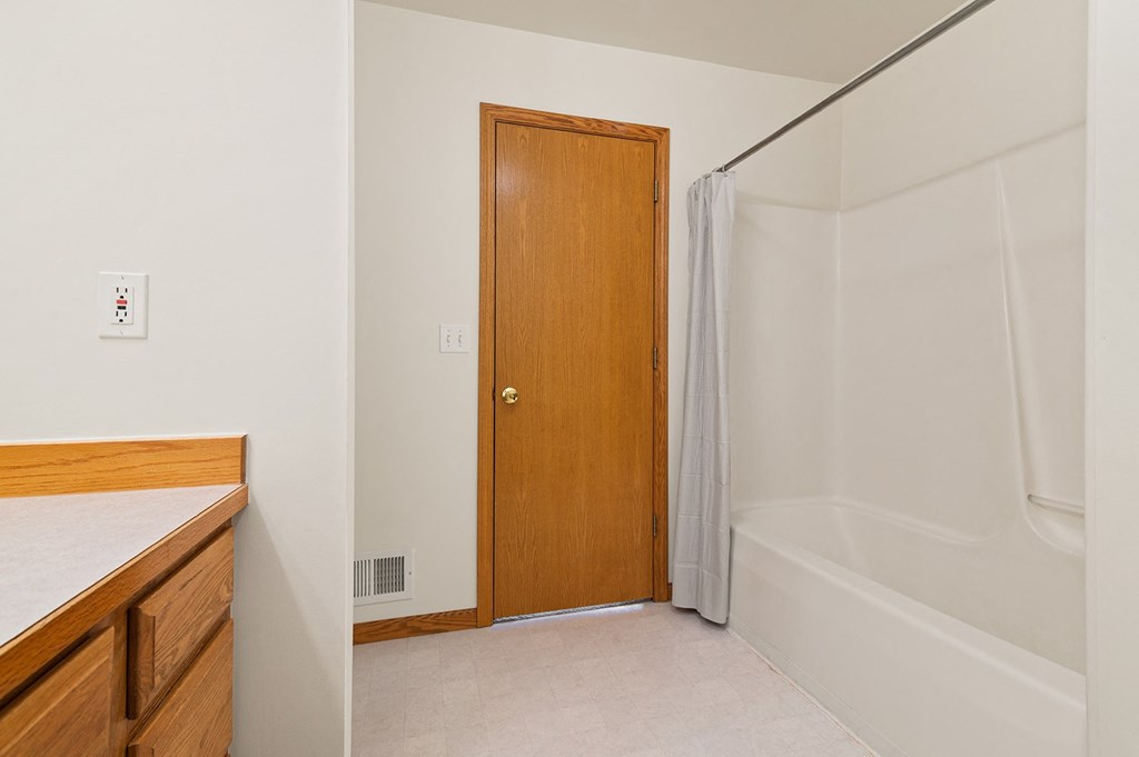a bathroom with a shower and a wooden door     and a sink