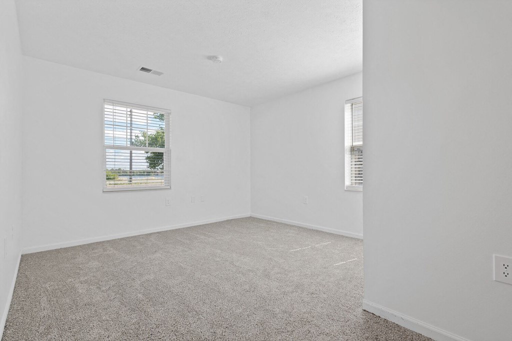 a bedroom with white walls and carpet