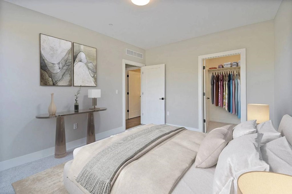 A bedroom with a large bed and a closet full of clothes.