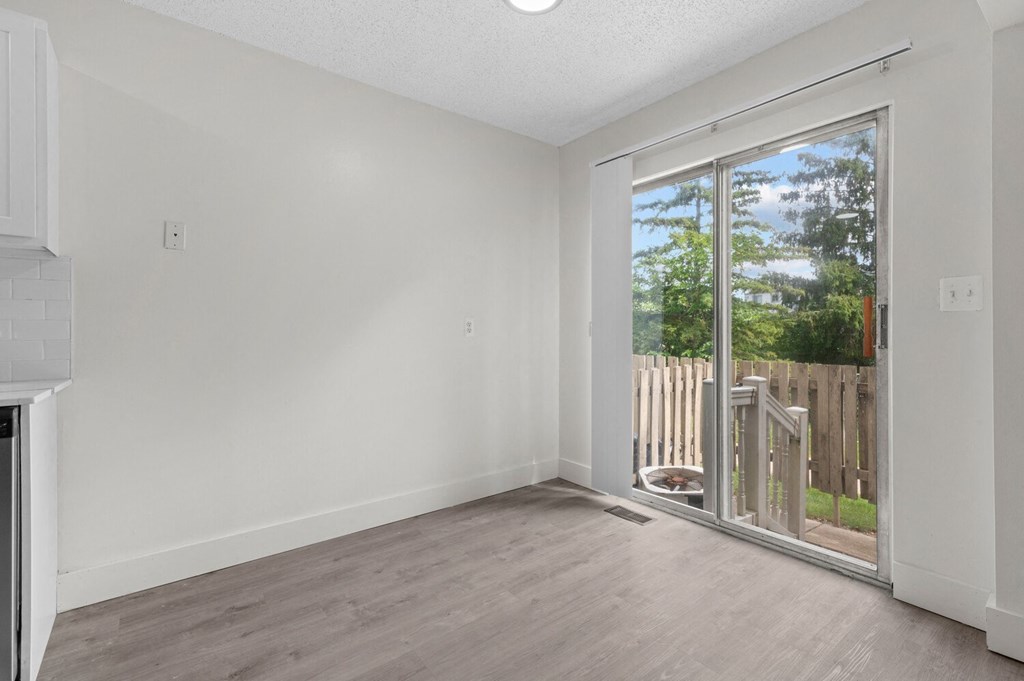 an empty living room with a sliding glass door to a balcony at Sterling Lake - Sterling Heights, MI, Michigan