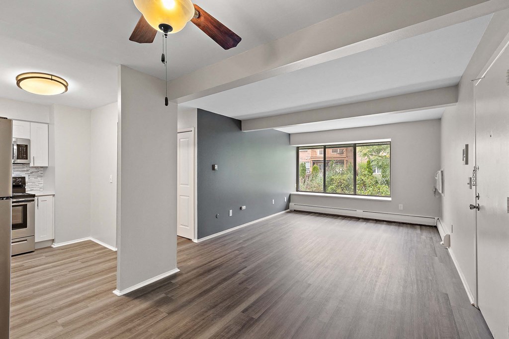 an empty living room with a ceiling fan and a window