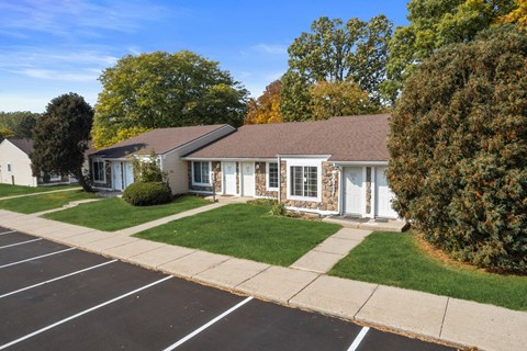 a white house with blue shutters and a lawn and sidewalk