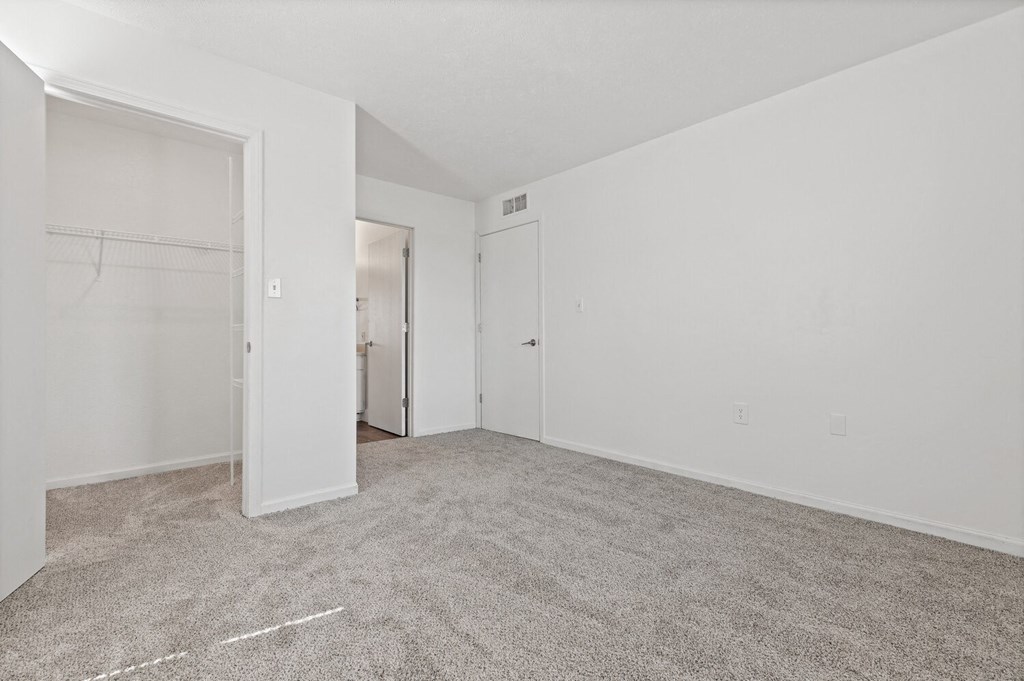 a bedroom with white walls and carpet