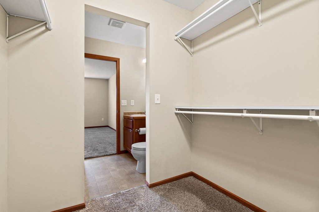 an empty bathroom with a toilet and a walk in closet