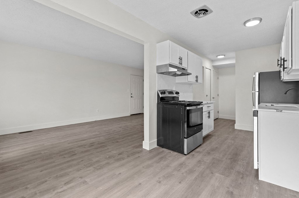 an empty kitchen and living room with white walls and wood flooring at Sterling Lake - Sterling Heights, MI, Michigan, 48312