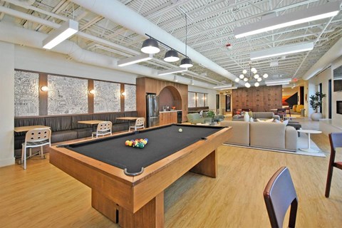 A pool table is in the middle of a room with a couch and chairs.