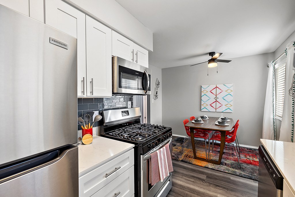 spacious kitchen with stainless steel appliances and white cabinets and a dining room table with chairs