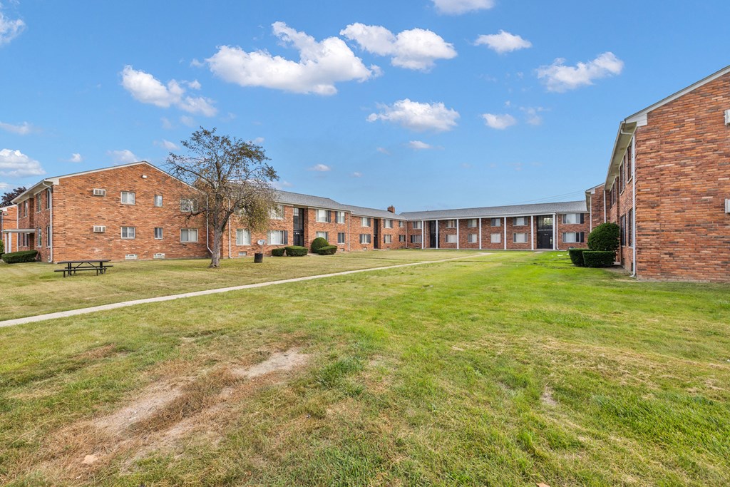 the courtyard of a large brick building with a grassy field