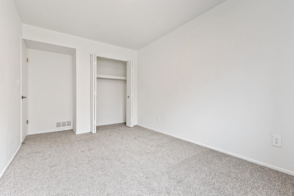 an empty room with white walls and a door to a closet